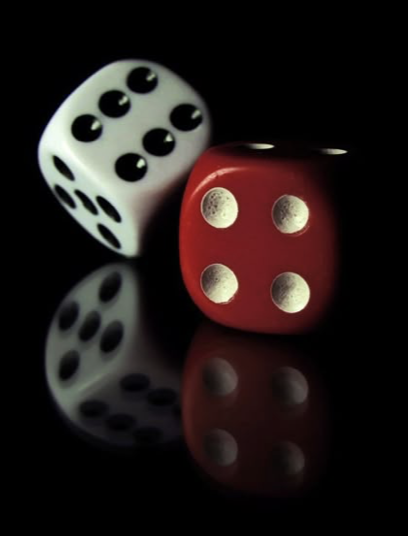 A pair of dice resting on a reflective black surface